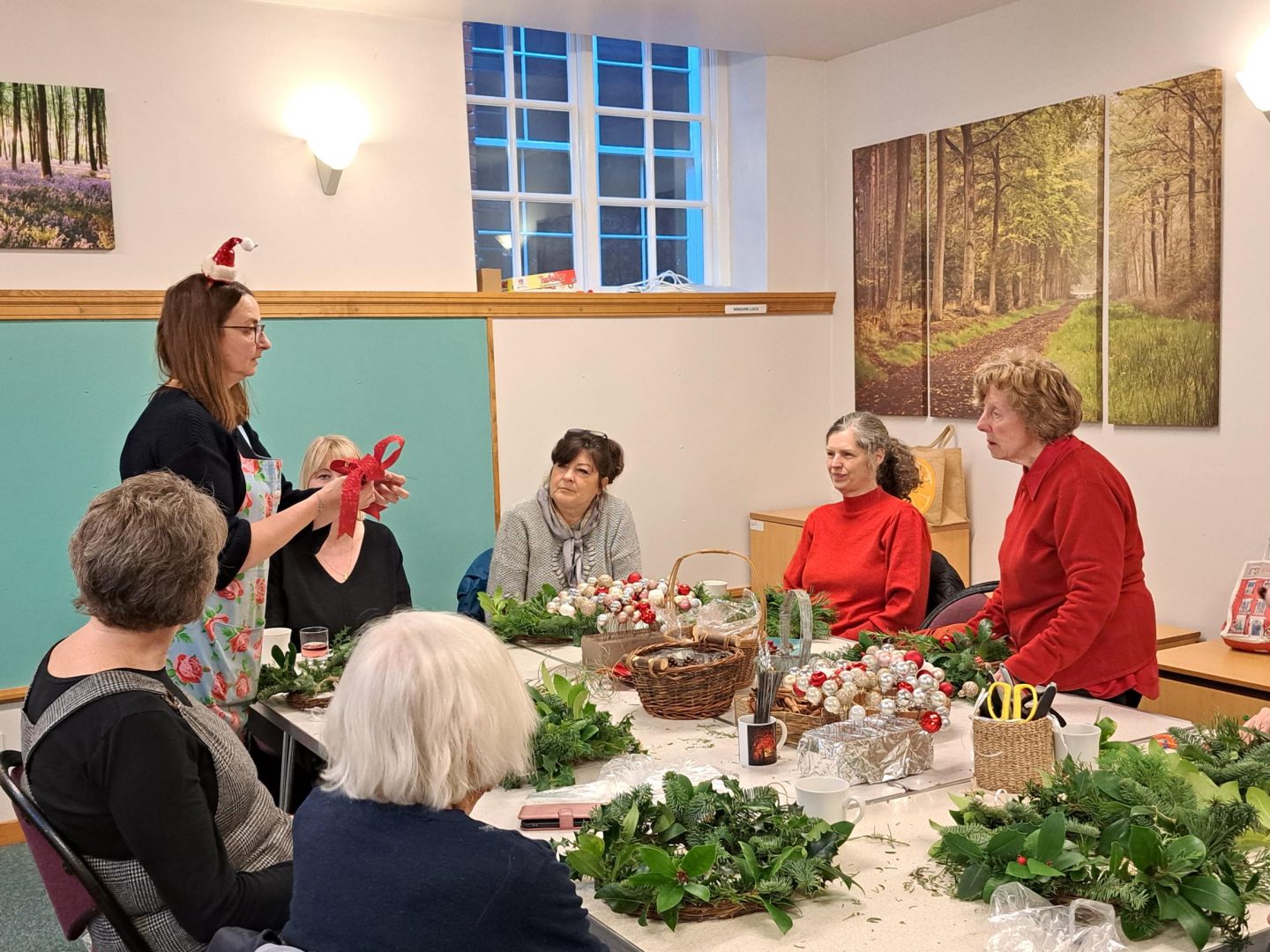 people sat around a table making christmas wreaths